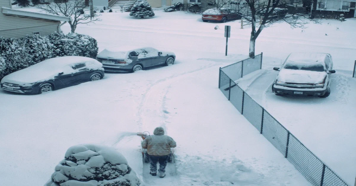 Personne qui déblaie la neige dans une entrée de maison en hiver